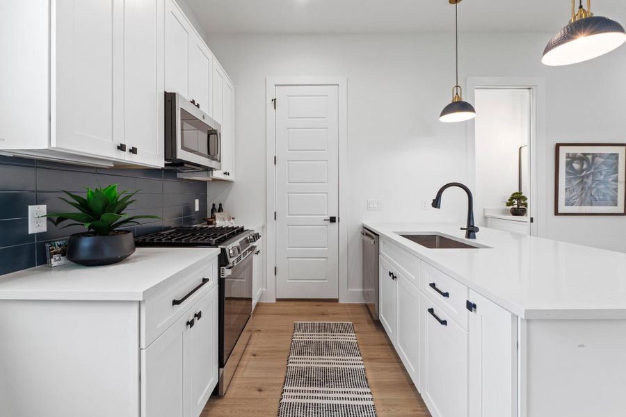 Streamlined cabinetry and quartz countertops frame a modern culinary workspace with warm wood flooring.