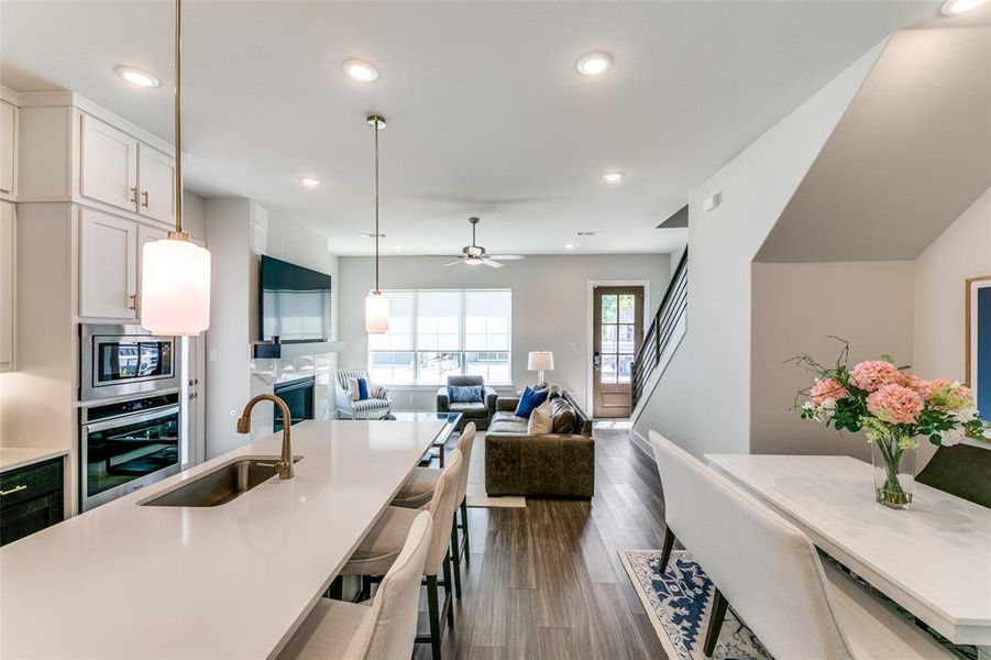 Kitchen with a kitchen breakfast bar, stainless steel appliances, dark wood-type flooring, sink, and white cabinets