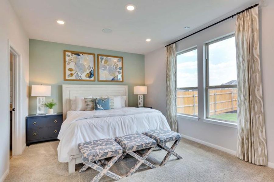 Bedroom featuring light colored carpet and multiple windows