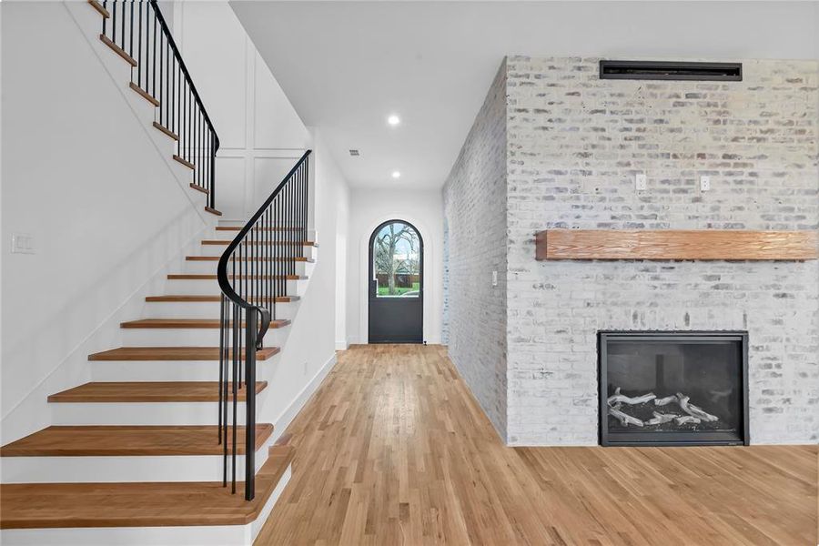 Foyer entrance with recessed lighting, light wood-style flooring, a fireplace, and brick wall
