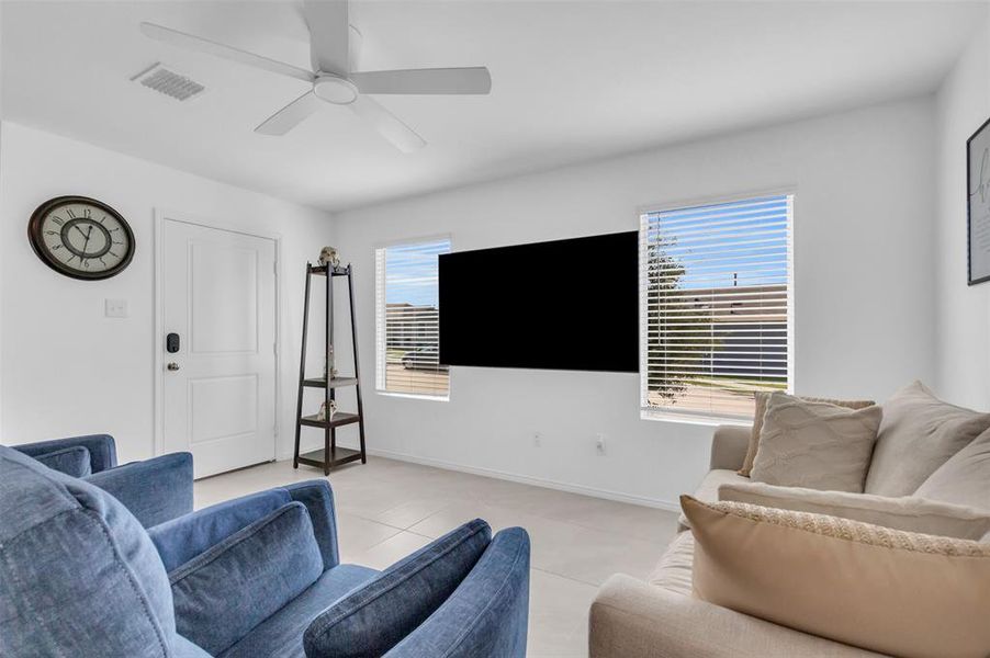 Tiled living room with plenty of natural light and ceiling fan