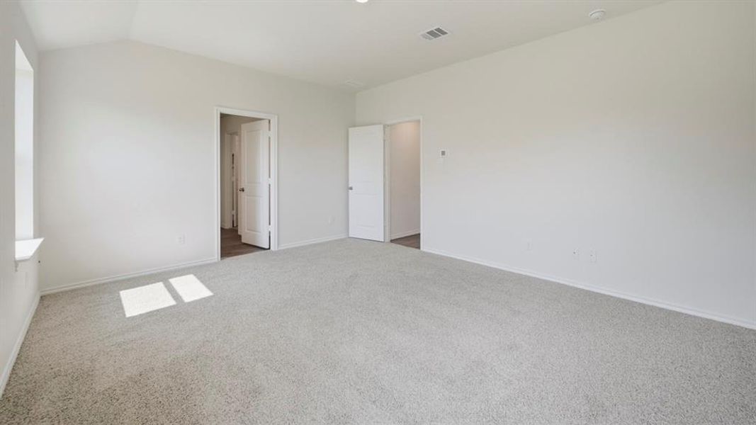 Unfurnished bedroom with carpet floors and vaulted ceiling Unfurnished bedroom with carpet floors and vaulted ceiling
