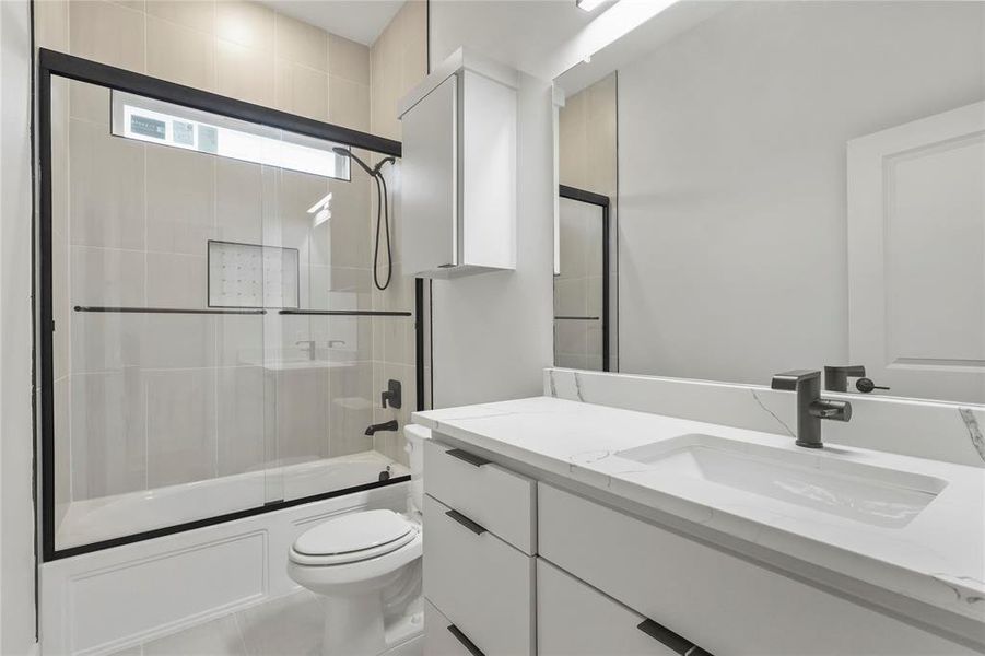 Bathroom with bath / shower combo with glass door and vanity