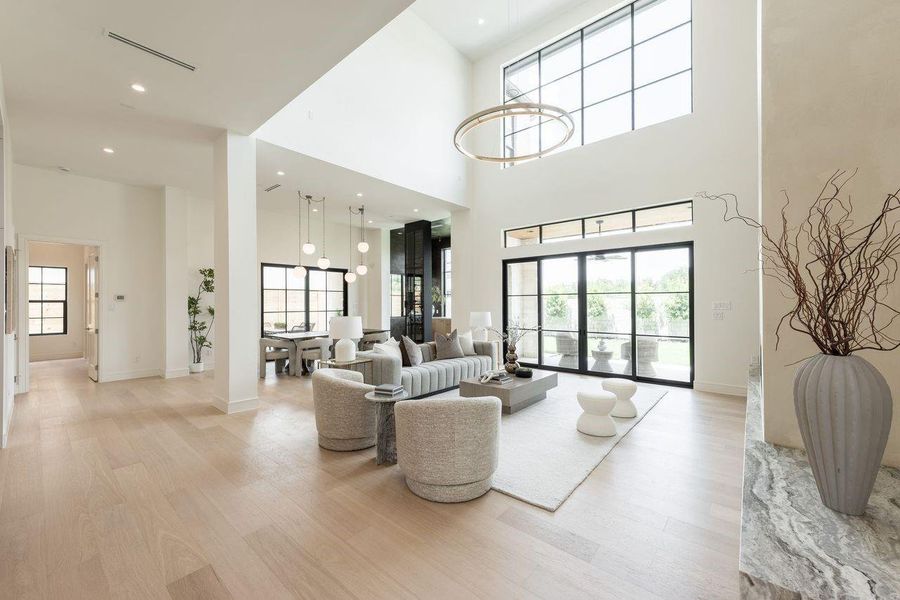 Dramatic in scale yet grounded in warmth, this double-height living space is framed by oversized windows and sleek sliding doors that open to a private outdoor retreat. Layered lighting, tailored textures, and architectural volume converge to create a refined environment designed for gathering and unwinding alike.