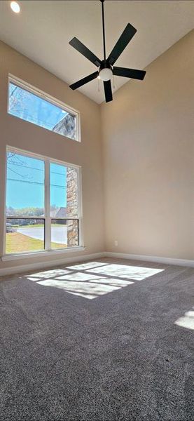Empty room with ceiling fan, 15 ft high ceiling, carpet floors and natural lighting Empty room with ceiling fan, 15 ft high ceiling, carpet floors and natural lighting