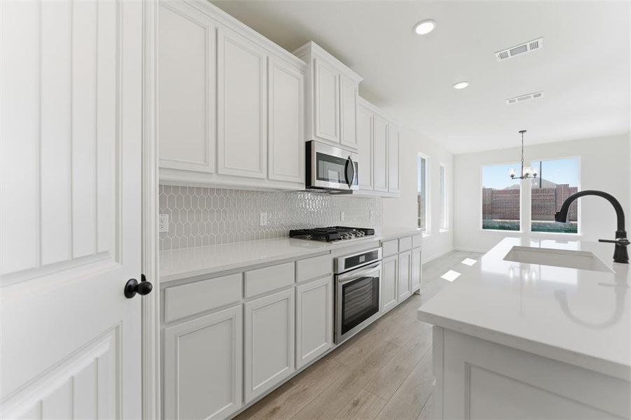 Kitchen featuring white cabinets, appliances with stainless steel finishes, pendant lighting, decorative backsplash, and recessed lighting