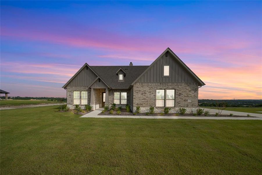 Modern farmhouse style home with board and batten siding, a front yard, brick siding, and a chimney Modern farmhouse style home with board and batten siding, a front yard, brick siding, and a chimney