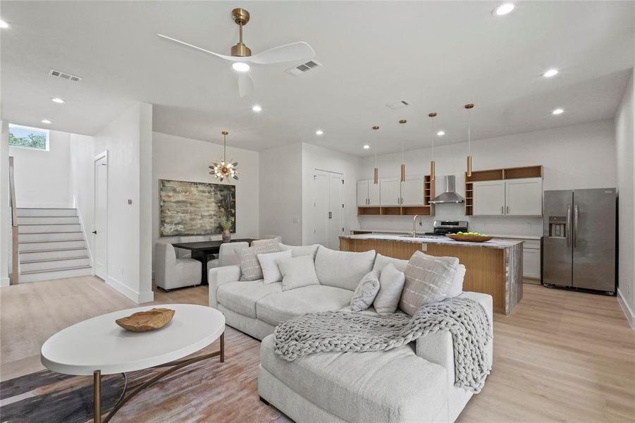 Living room featuring sink, ceiling fan with notable chandelier, and light wood-type flooring