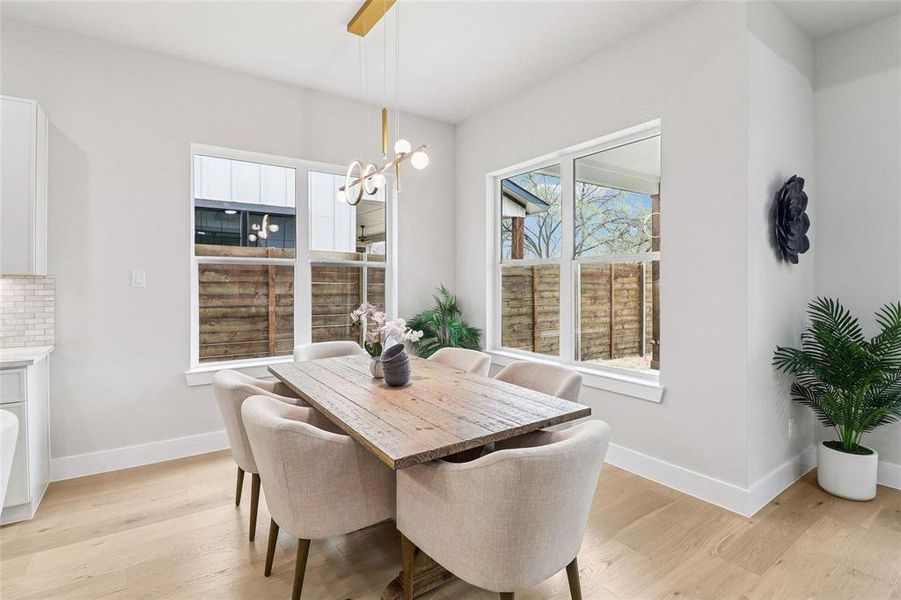 Dining area featuring light hardwood floors, white walls, and a modern chandelier