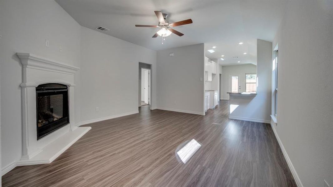 Unfurnished living room featuring a fireplace with raised hearth, recessed lighting, ceiling fan, dark wood finished floors, and vaulted ceiling