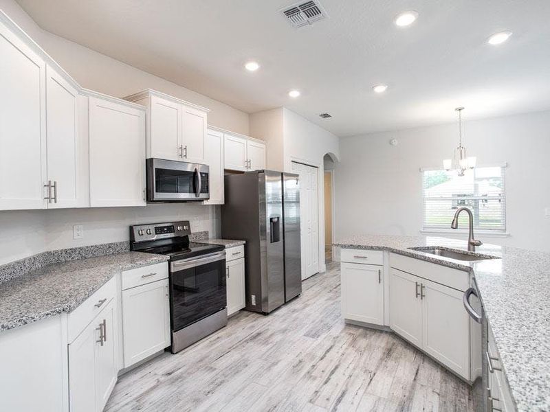 Enjoy a bright and open kitchen with a large island, pantry, and ample counter space - Willow II with Loft by Highland Homes Enjoy a bright and open kitchen with a large island, pantry, and ample counter space - Willow II with Loft by Highland Homes