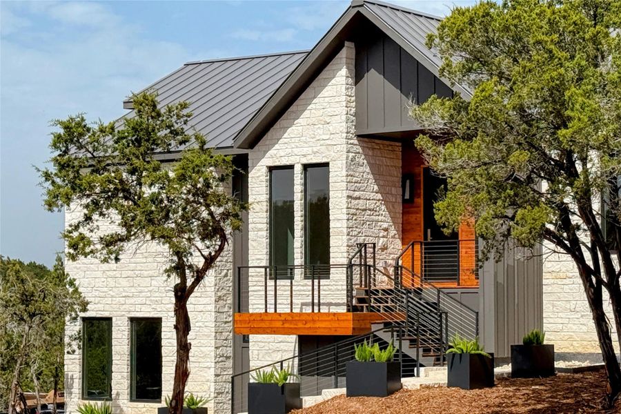 View of side of home with stone siding, board and batten siding, metal roof, and a standing seam roof