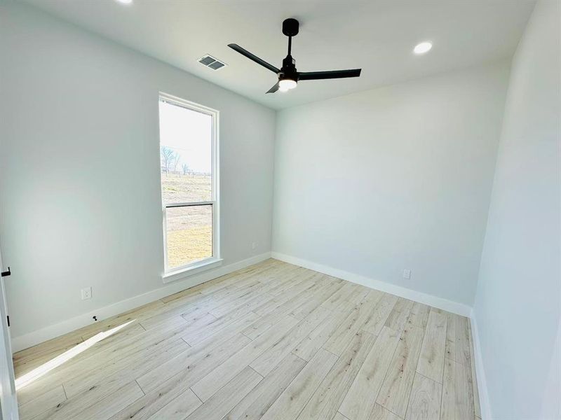 Empty room featuring a healthy amount of sunlight, ceiling fan, and light hardwood / wood-style floors