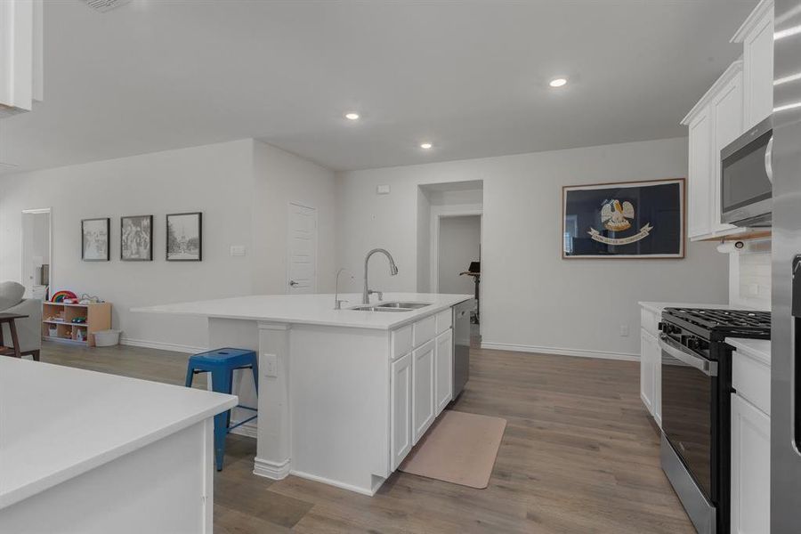 Kitchen with stainless steel appliances, white cabinets, a sink, and dark wood-type flooring