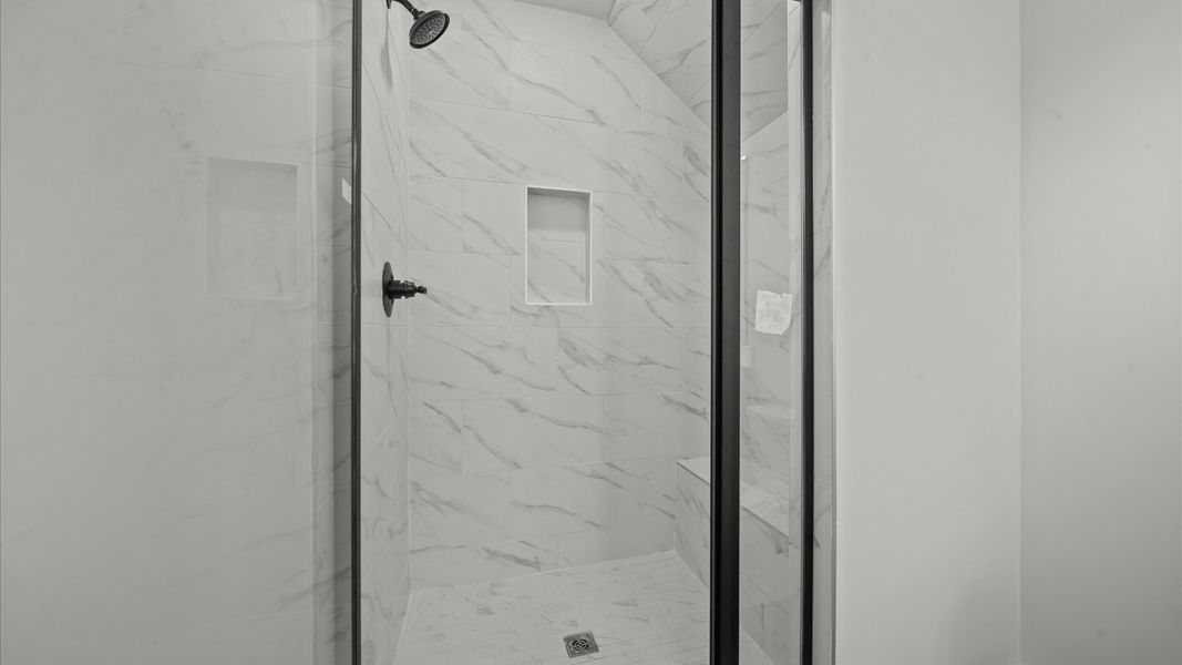 Spacious and modern primary bathroom with tiled walk-in shower and first-class double vanity setup