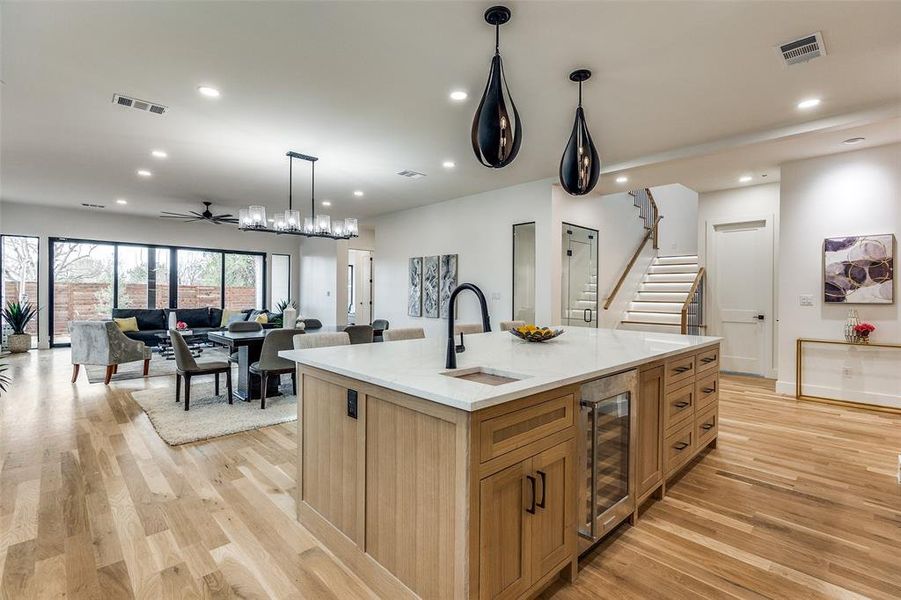 Kitchen with ceiling fan, beverage cooler, sink, pendant lighting, and an island with sink