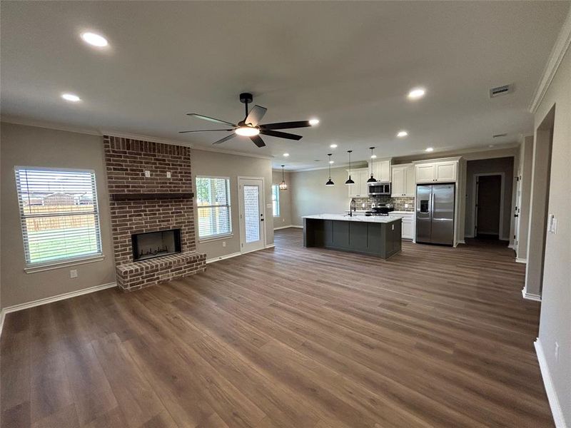 Kitchen featuring open floor plan, crown molding, hanging light fixtures, appliances with stainless steel finishes, and white cabinets