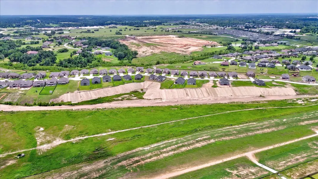 A sweeping aerial view showcasing the full row of Waterstone homes along the greenbelt. The gently sloping lots and unobstructed rear views offer an ideal mix of beauty and privacy.