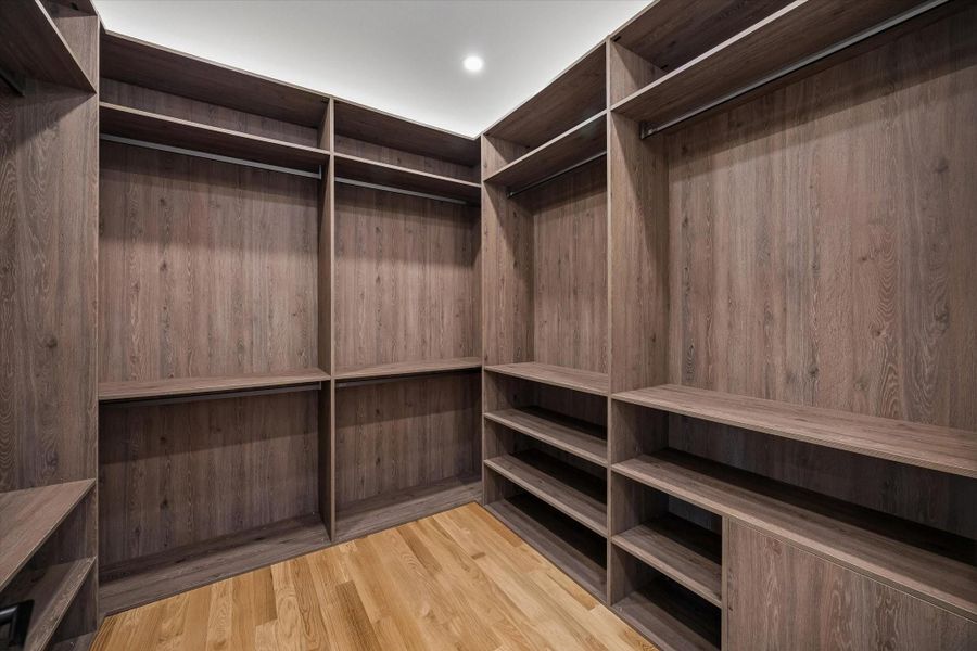 Spacious walk-in closet with custom wood shelving and ample hanging space, perfect for organizing your wardrobe. Spacious walk-in closet with custom wood shelving and ample hanging space, perfect for organizing your wardrobe.