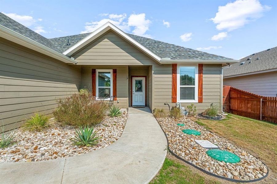Doorway to property featuring a shingled roof and a porch