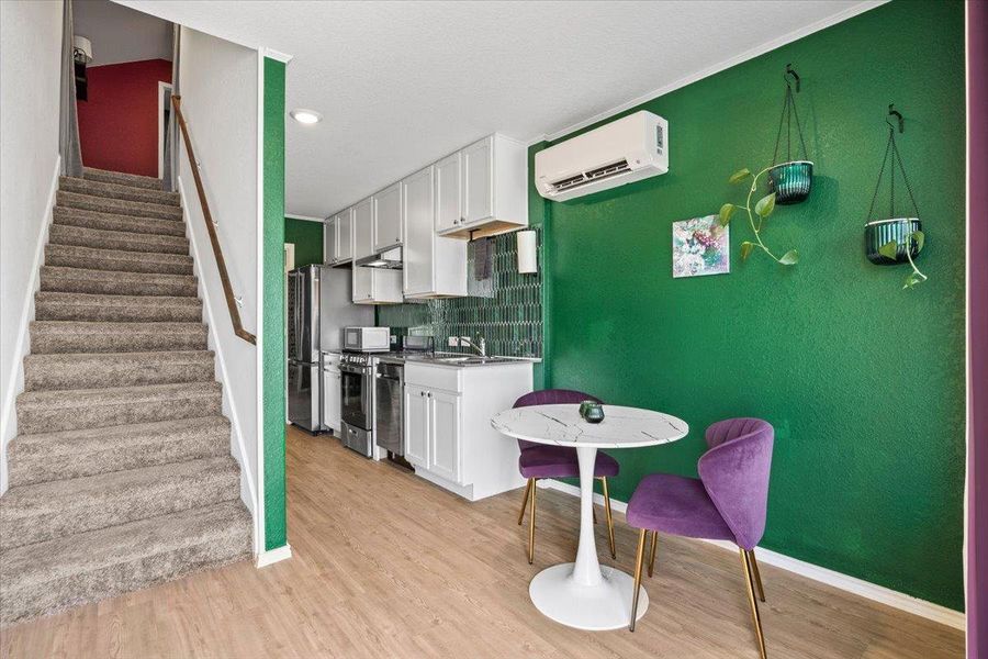 Kitchen featuring white cabinets, light wood-type flooring, tasteful backsplash, and stainless steel appliances Kitchen featuring white cabinets, light wood-type flooring, tasteful backsplash, and stainless steel appliances