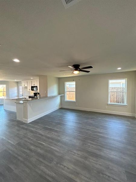 Lliving room featuring ceiling fan, wood-style flooring, and windows that allow natural light