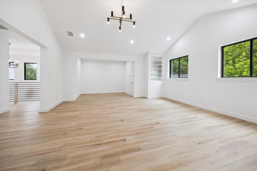 An alternate view of the upstairs game room highlights a spacious niche ideal for a game table or media setup. The open-concept design, built-in shelving, and natural light make this a flexible space for entertaining or relaxing. An alternate view of the upstairs game room highlights a spacious niche ideal for a game table or media setup. The open-concept design, built-in shelving, and natural light make this a flexible space for entertaining or relaxing.