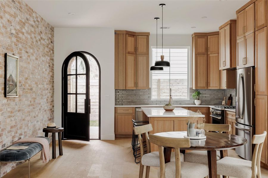 Kitchen featuring brick wall, freestanding refrigerator, a kitchen island, high end black range oven, and light wood-style flooring