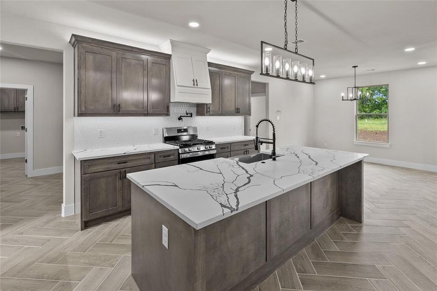 Kitchen featuring stainless steel range with gas stovetop, a sink, baseboards, recessed lighting, and tasteful backsplash