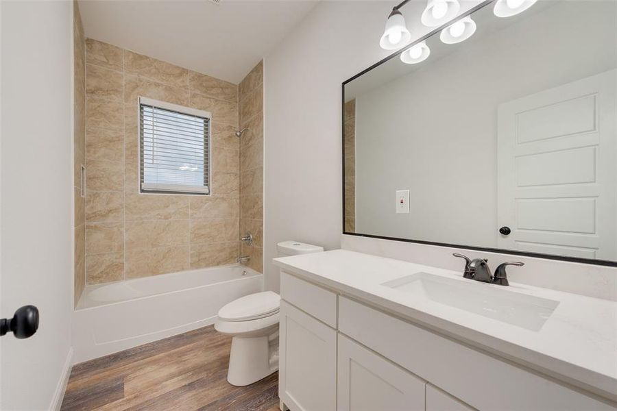 Full bathroom with vanity, toilet, hardwood / wood-style flooring, and tiled shower / bath combo