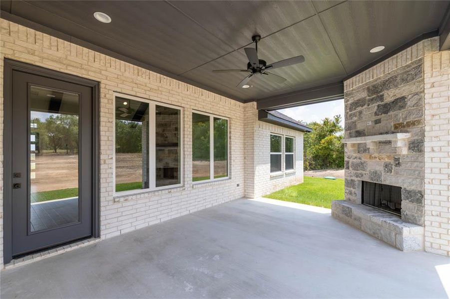 View of patio featuring an outdoor stone fireplace and ceiling fan