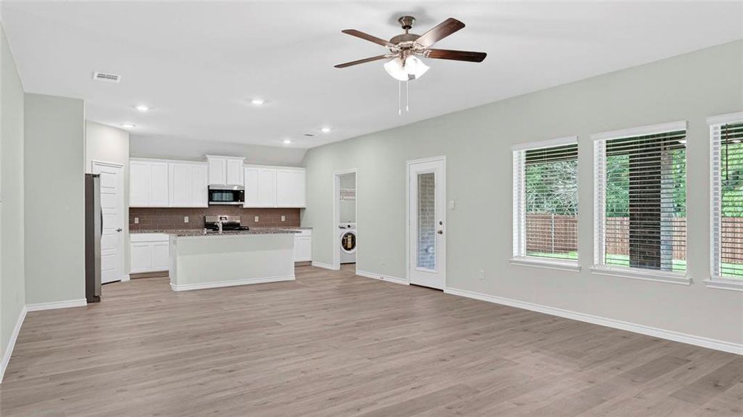 Open-concept living area featuring wood-finish flooring and a ceiling fan with integrated lighting