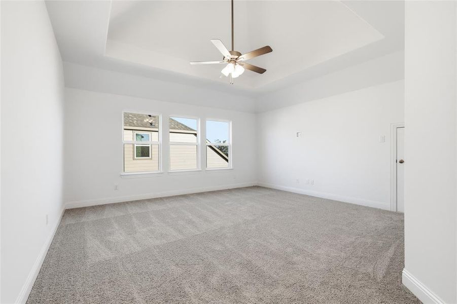 Empty room with light colored carpet, a ceiling fan, and a tray ceiling Empty room with light colored carpet, a ceiling fan, and a tray ceiling