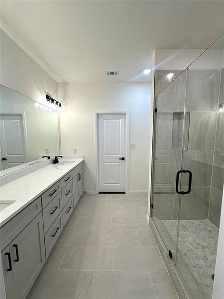 Bathroom featuring tile patterned flooring, vanity, and a shower with shower door