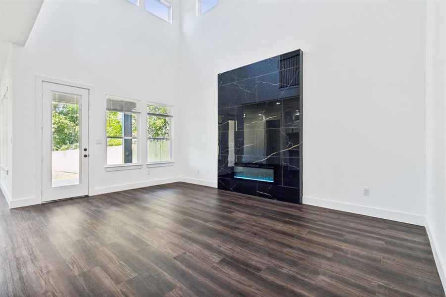 Unfurnished living room featuring a fireplace, a high ceiling, and dark hardwood / wood-style flooring