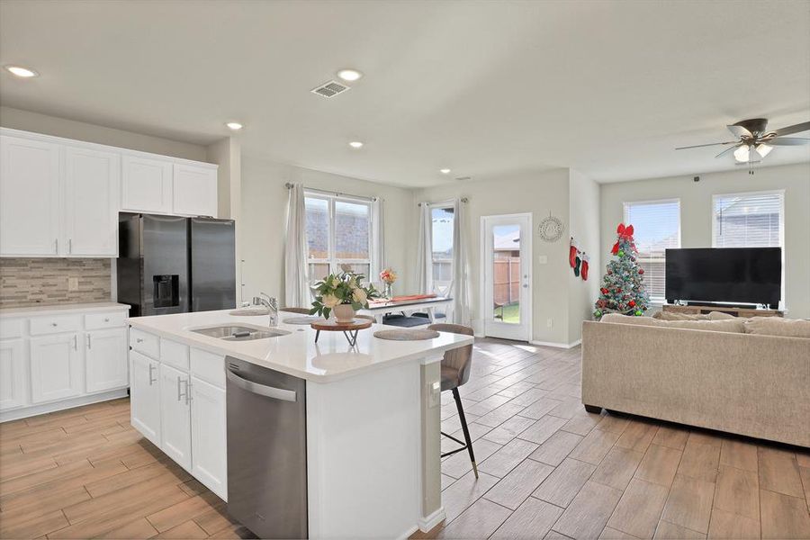 Kitchen with a kitchen island with sink, white cabinets, sink, light hardwood / wood-style floors, and stainless steel appliances