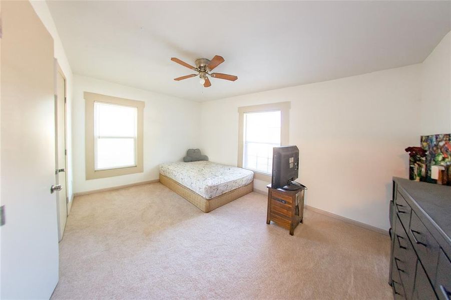Bedroom with multiple windows, light carpet, and ceiling fan