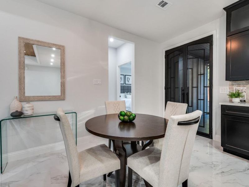 Dining area featuring light marble finish floors and recessed lighting.