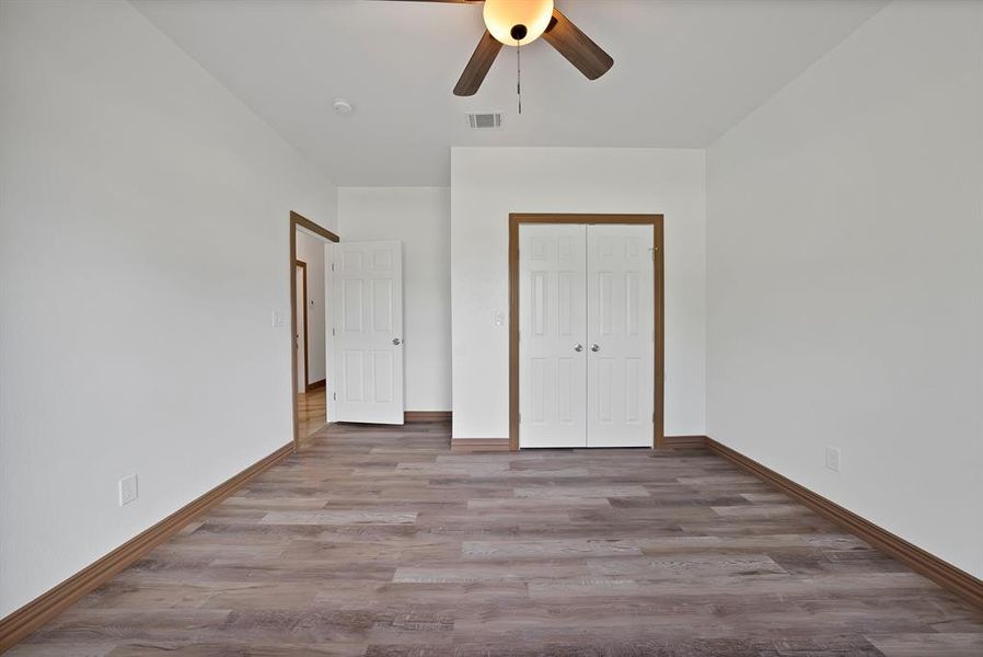 Unfurnished bedroom featuring wood finished floors, a closet, and a ceiling fan