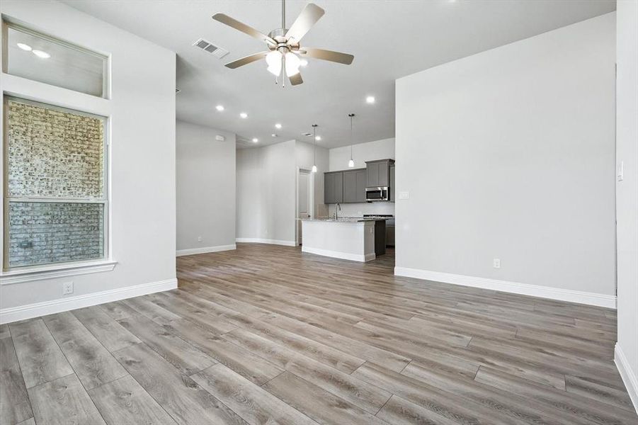 Unfurnished living room with a ceiling fan, recessed lighting, and light wood-type flooring Unfurnished living room with a ceiling fan, recessed lighting, and light wood-type flooring