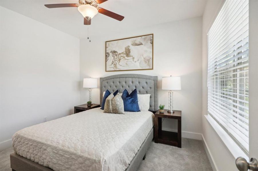 Bedroom with ceiling fan and light colored carpet