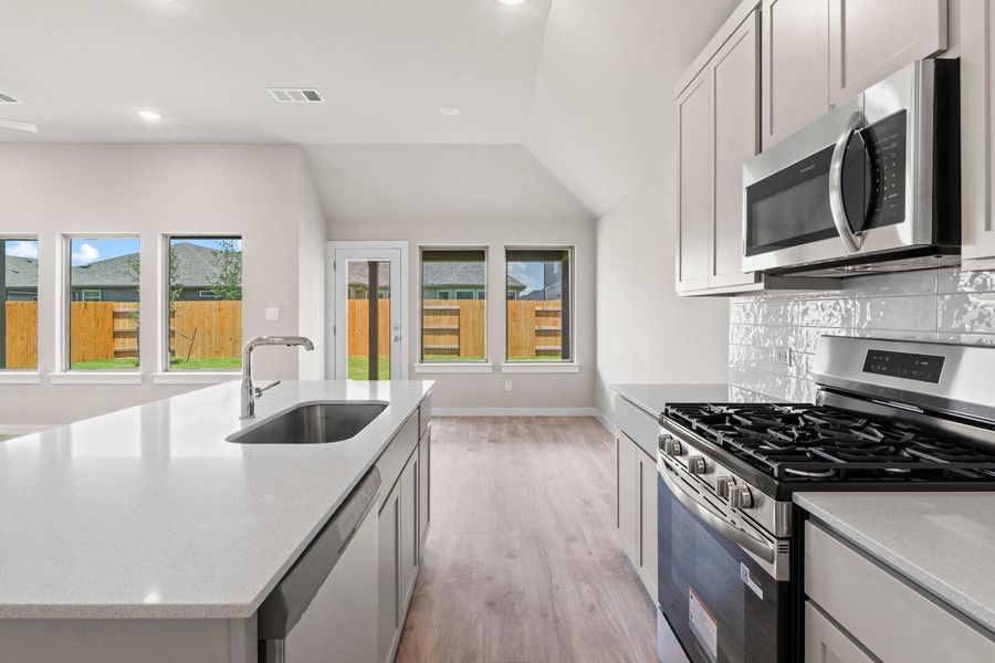 A well-appointed kitchen showcases sleek stainless steel appliances, a generous island, and ample natural light from backyard-facing windows.
