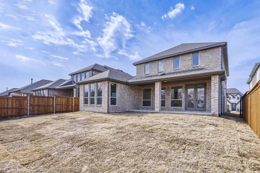 Back of house with brick siding, a patio area, a fenced backyard, and roof with shingles