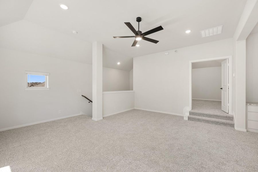 Spacious bonus room with carpet, ceiling fan, vaulted ceiling, and open doorway to adjacent room