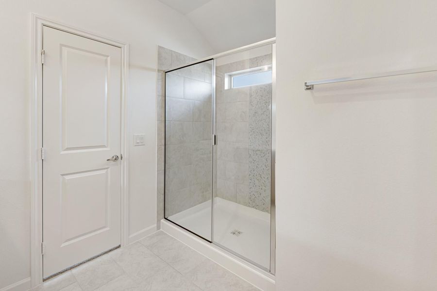 Walk-in shower with glass door, gray tile walls, and small window in white bathroom Walk-in shower with glass door, gray tile walls, and small window in white bathroom