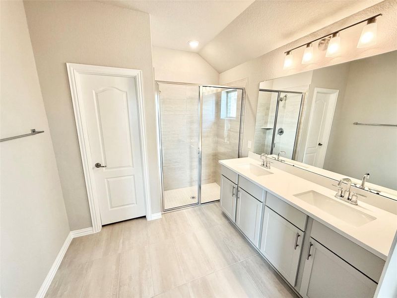 Full bath with a stall shower, lofted ceiling, double vanity, and light tile patterned floors Full bath with a stall shower, lofted ceiling, double vanity, and light tile patterned floors