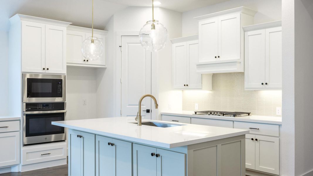 Kitchen with oven, white cabinetry, backsplash, light countertops, and built in microwave Kitchen with oven, white cabinetry, backsplash, light countertops, and built in microwave