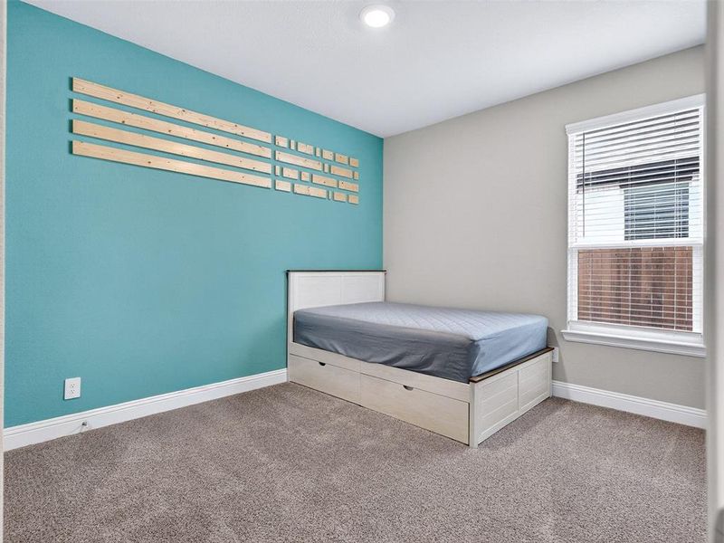 Carpeted room with a teal accent wall, recessed lighting, and a single window featuring blinds Carpeted room with a teal accent wall, recessed lighting, and a single window featuring blinds