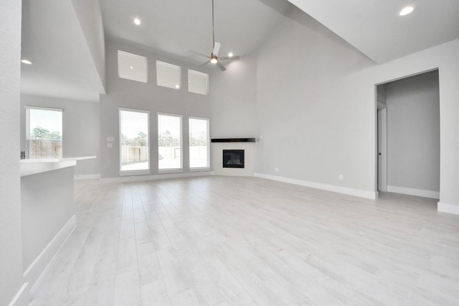 Relax and unwind in this inviting family room, illuminated by abundant natural light streaming in through tall windows, complemented by high ceilings and stunning flooring. Stay comfortable year-round with the gentle breeze from the ceiling fan, creating the perfect atmosphere for family gatherings.