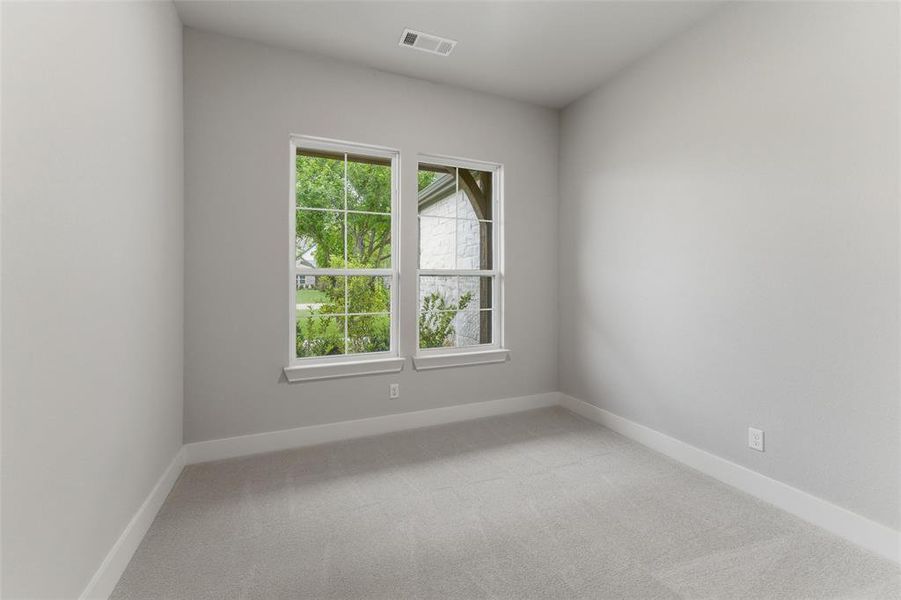 Soft gray wall paint with white trim, light gray carpet, and two large windows offering natural light